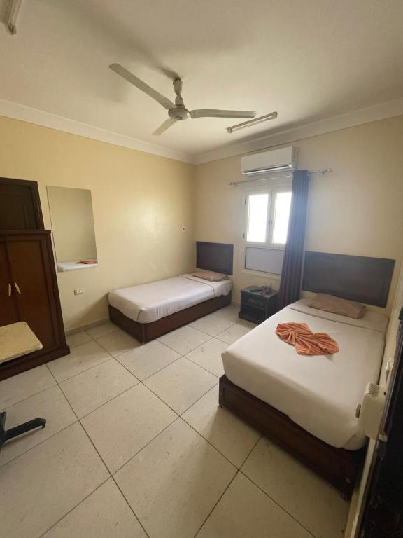 1 dormitorio con 2 camas y ventilador de techo en Makkah Hotel, en Qinā