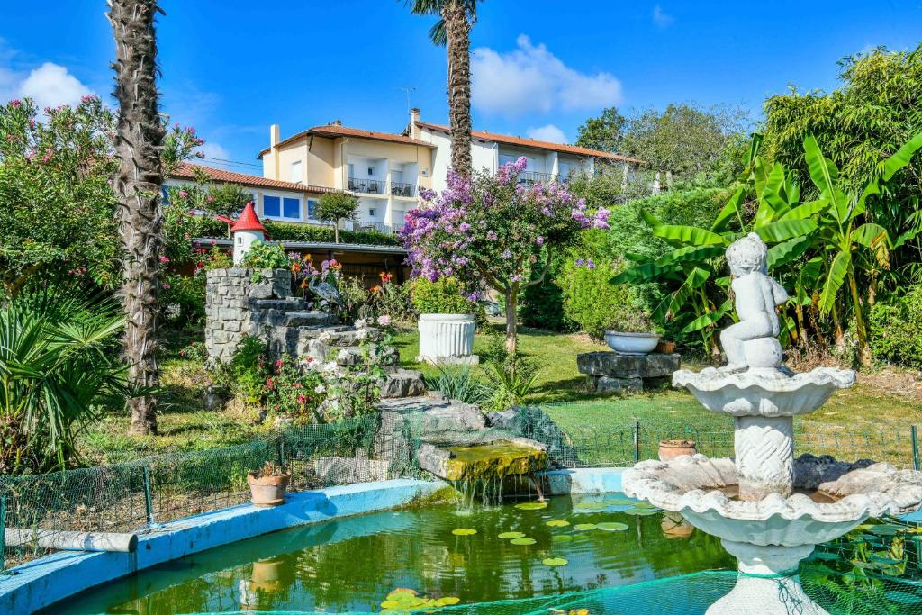 a garden with a fountain in front of a house at Logis Hôtel & Restaurant Aux Tauzins in Montfort-en-Chalosse