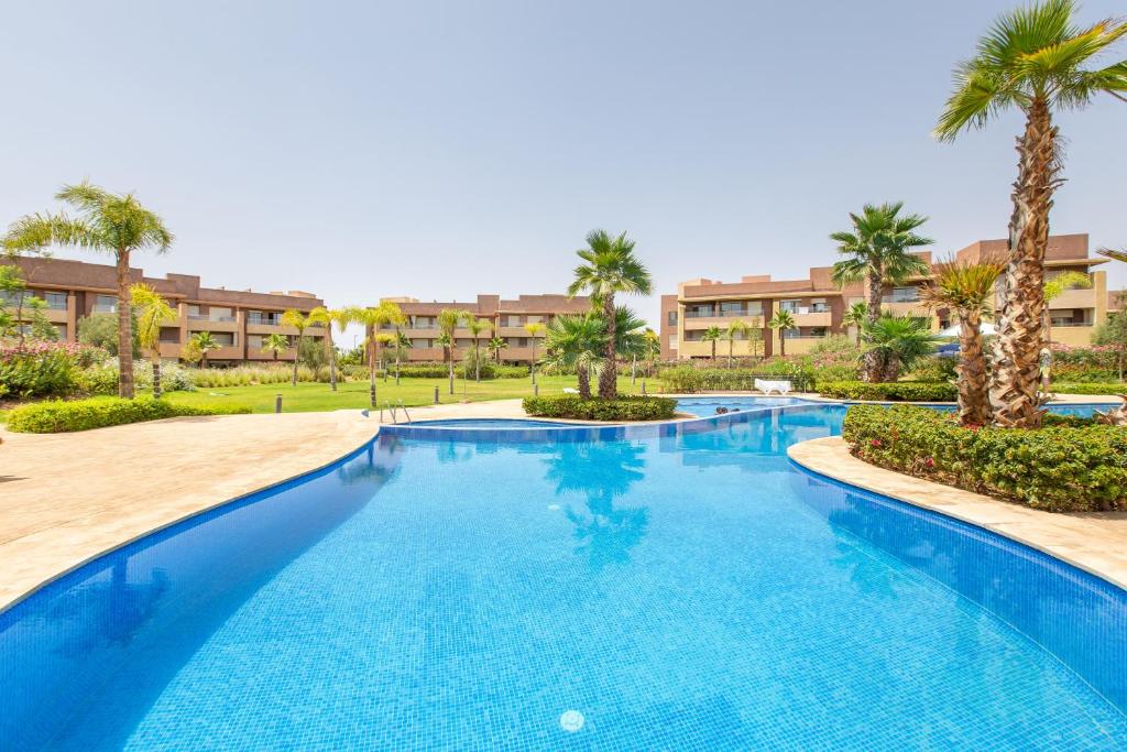 uma grande piscina com palmeiras e condomínios em Appartement Pied dans l'Eau - jardin privée em Marrakech