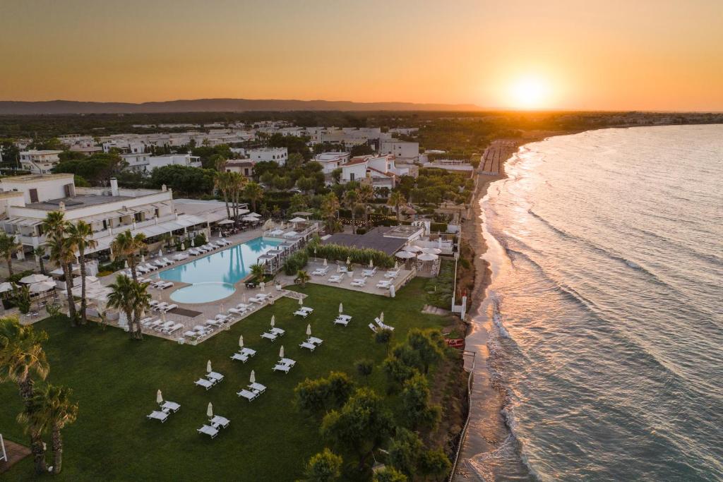 una vista aerea di un resort e dell'oceano al tramonto di Canne Bianche Lifestyle Hotel a Torre Canne