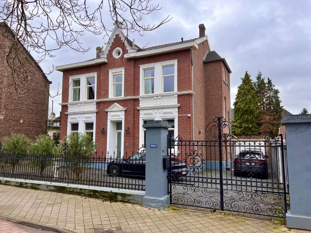 a red brick house with a gate and a fence at Villa Aix in Kerkrade