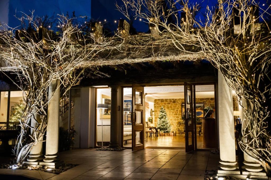 Una entrada a un edificio con árboles y luces. en The Atlantic Hotel - Small Luxury Hotels of the World, en St Brelade