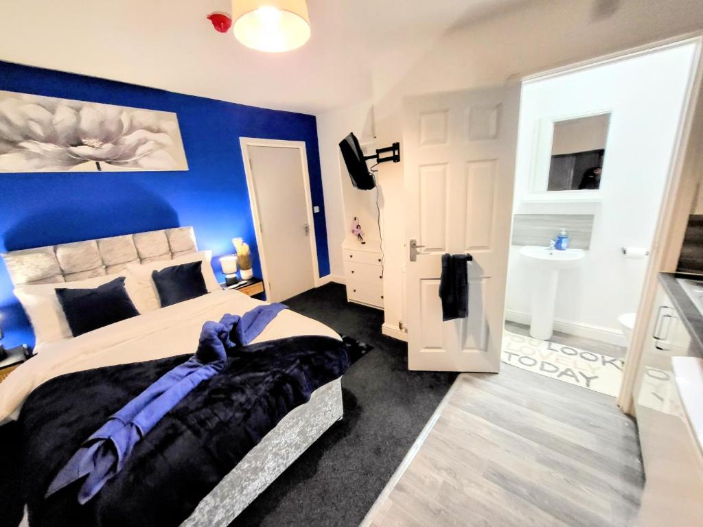 a bedroom with a large bed with a blue wall at Burford Road - Stay. Sleep. Rest. in Nottingham