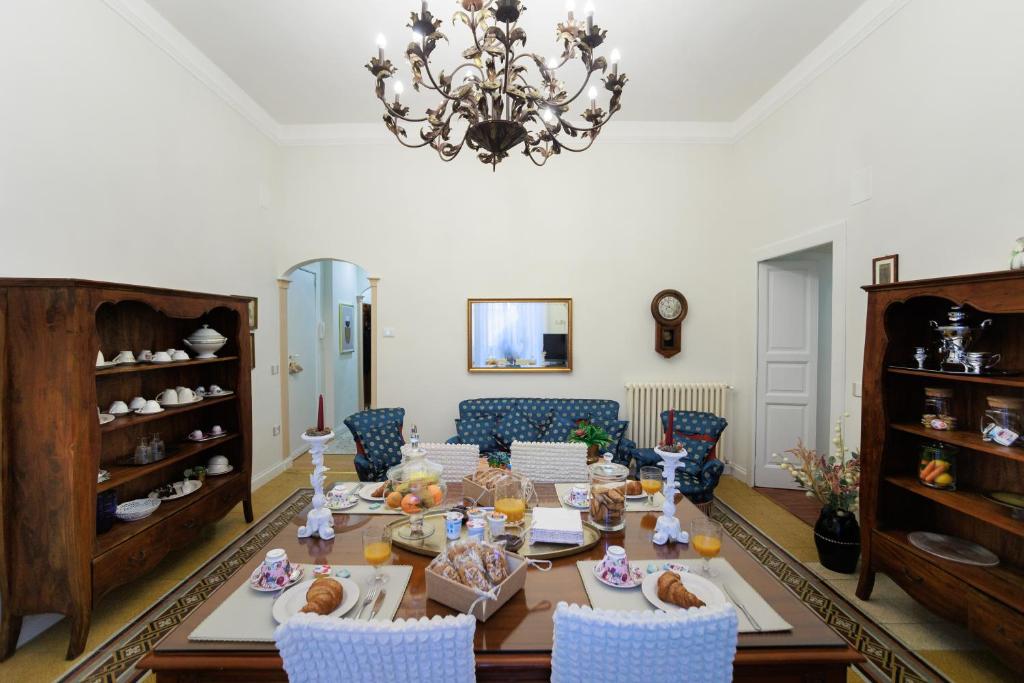 una sala da pranzo con tavolo, sedie e lampadario pendente di B&B CORSO VITTORIO a Venosa