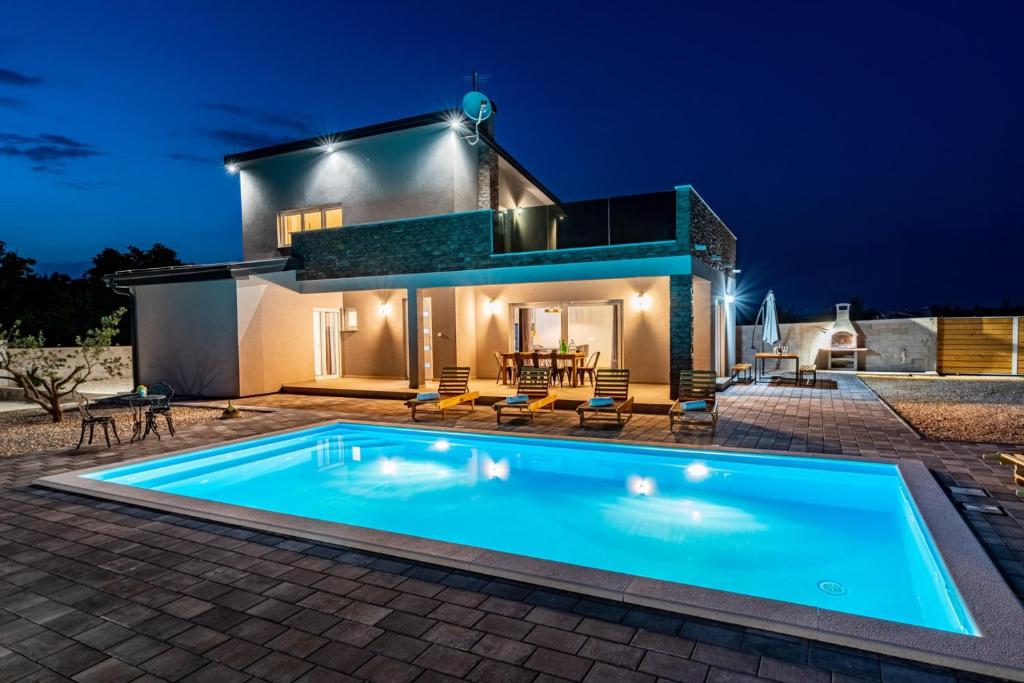 - une piscine en face d'une maison la nuit dans l'établissement Villa Grigia, à Banjevci