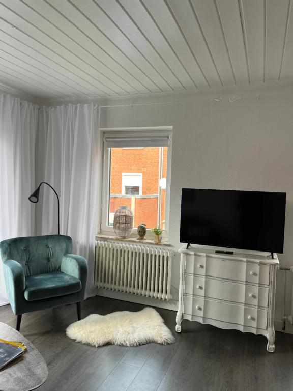een woonkamer met een flatscreen-tv en een stoel bij Quartier Lookvenne Wohnung 1 in Emden