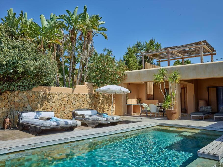 a house with a swimming pool with chairs and an umbrella at Kasbah 1 in Cala Vadella