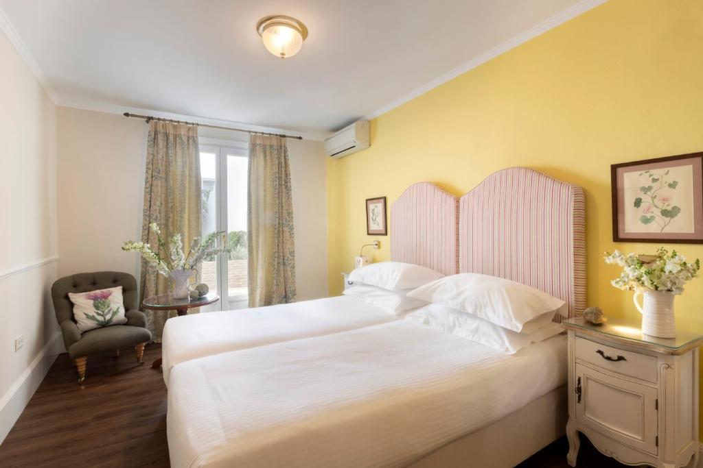 sypialnia z dużym białym łóżkiem i krzesłem w obiekcie Kouneni Apartments w mieście Mykonos