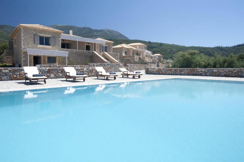 uma grande piscina com cadeiras e uma casa em Poliana Estate Villas em Riglia