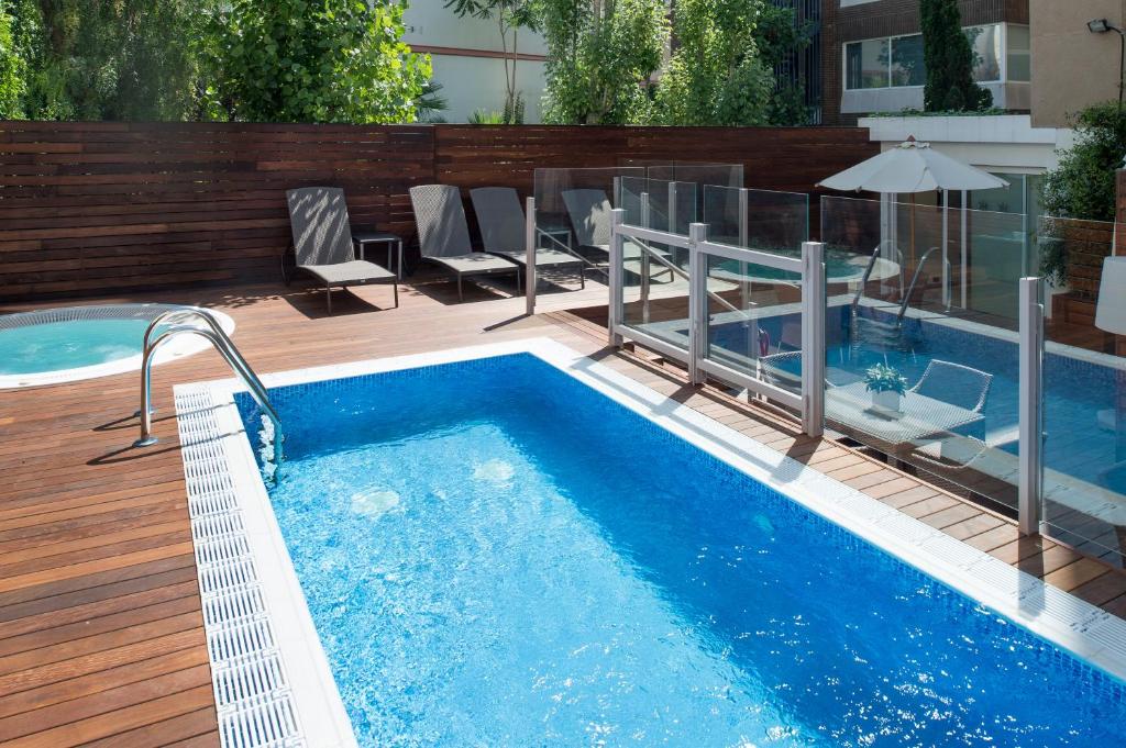 a pool with chairs and a table and an umbrella at Catalonia Mikado in Barcelona