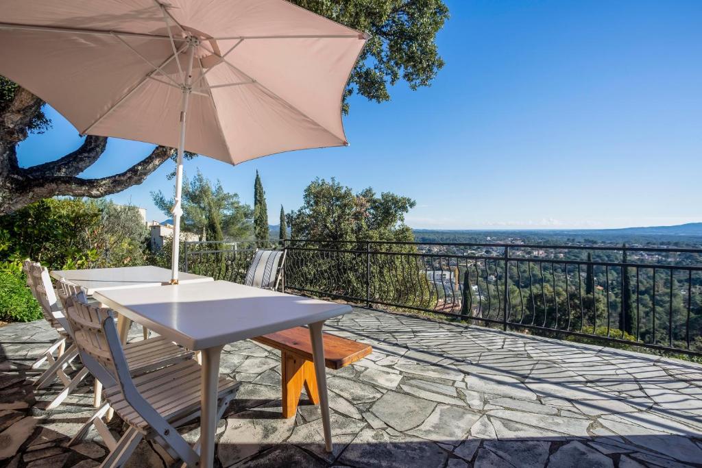 uma mesa e cadeira com um guarda-sol num pátio em Micaes - maison avec piscine privée em Roquebrune-sur-Argens