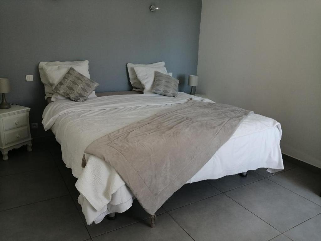 a bedroom with a large bed with white sheets and pillows at Mimosas - villa in Fréjus