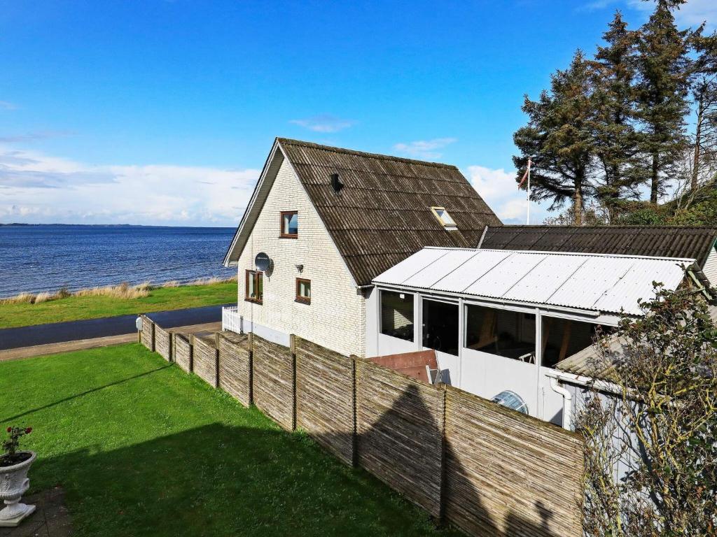 ein weißes Haus mit einem Zaun am Wasser in der Unterkunft Holiday home Farsø XI in Farsø