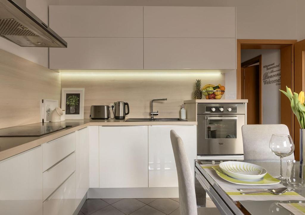 een keuken met witte kasten, een wastafel en een tafel bij Apartment Leki - newly renovated, modern city spot in Pula