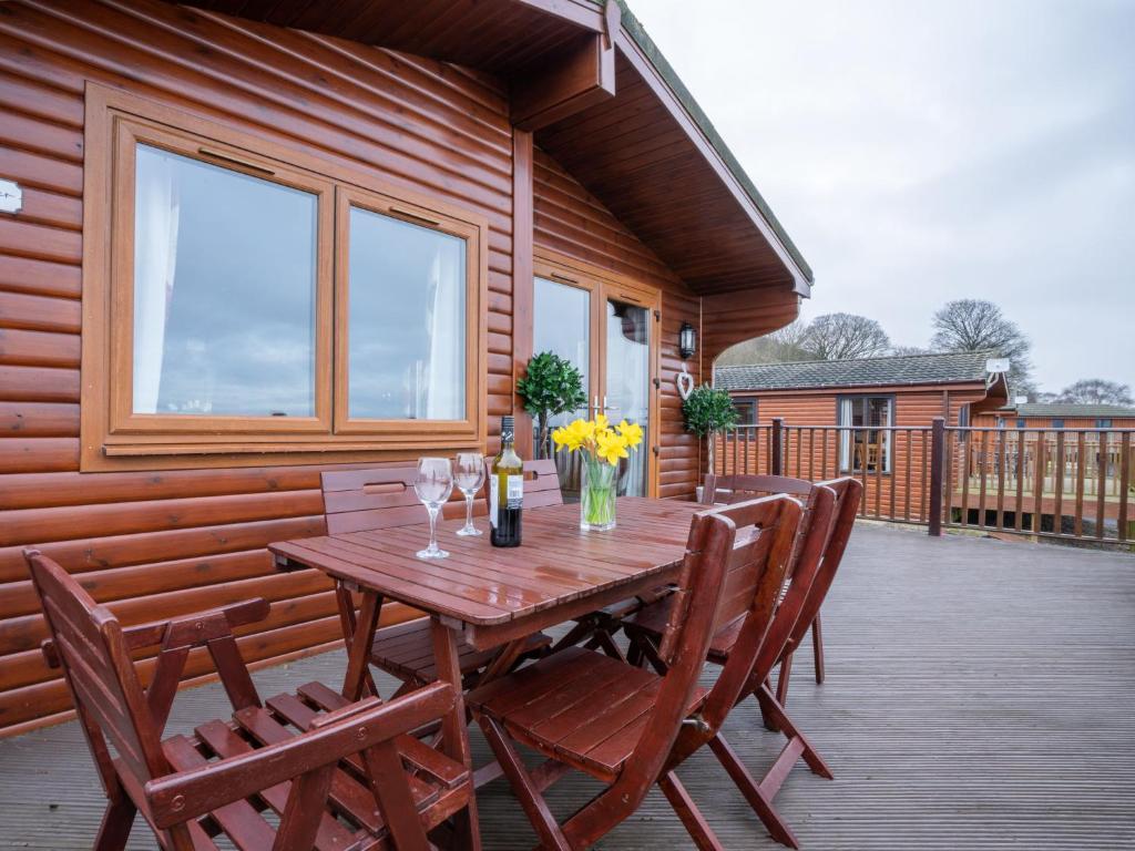 een houten tafel en stoelen op een terras bij Chalet Loch Leven Lodge 12 by Interhome in Kinross