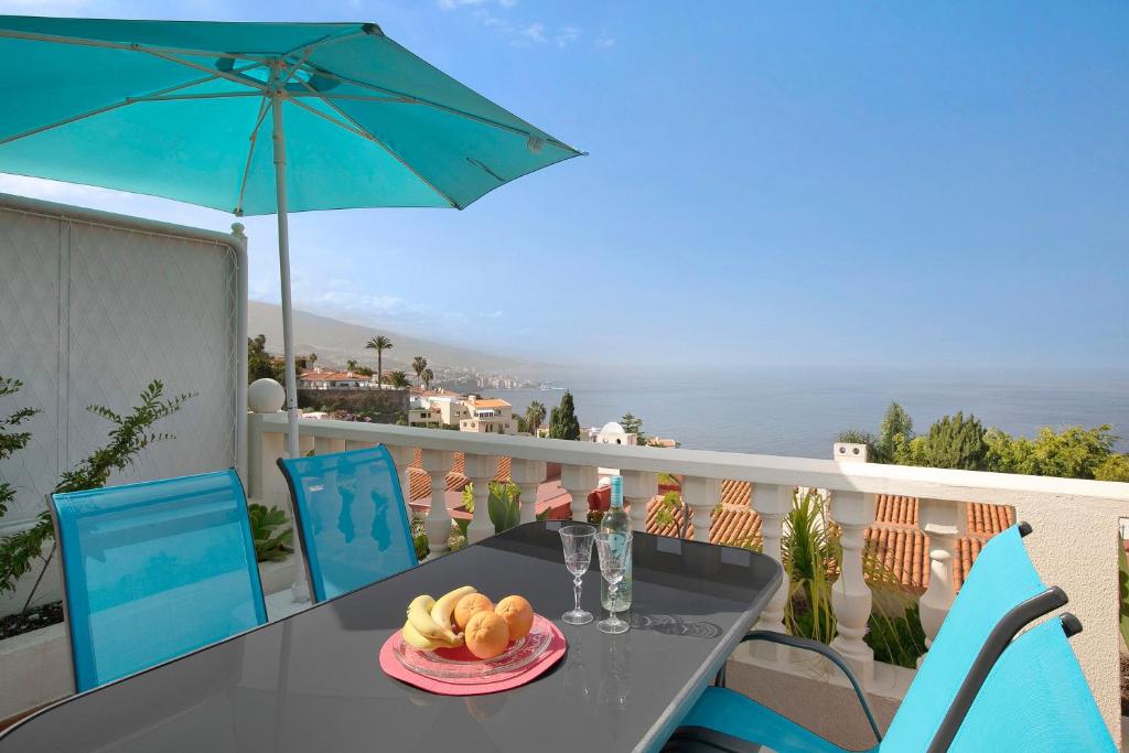 einen Tisch mit einem Teller Brot und einem Sonnenschirm auf dem Balkon in der Unterkunft casa Daniela in Santa Úrsula