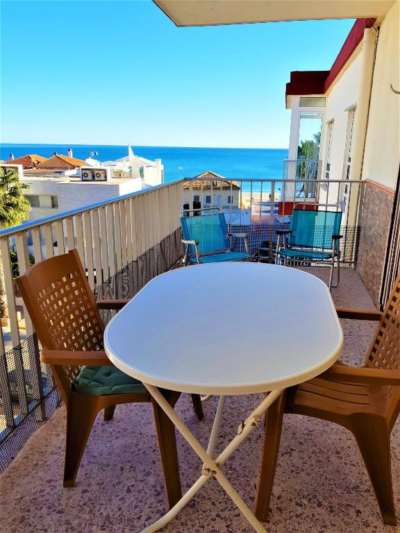 einen weißen Tisch und Stühle auf einem Balkon mit Meerblick in der Unterkunft 3 bedrooms appartement at Tavernes de la Valldigna 50 m away from the beach with sea view furnished terrace and wifi in El Brosquil