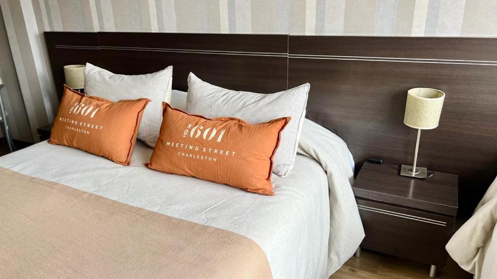 Una cama con almohadas naranjas y blancas. en Sarum Hotel Design en Buenos Aires