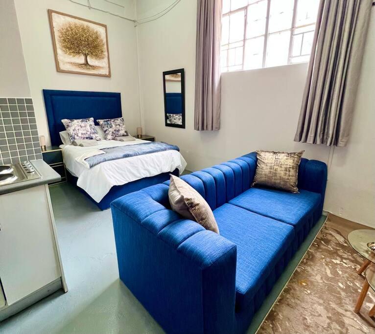1 dormitorio con sofá azul y cama en Cosy Apartment next to Maboneng, en Johannesburgo