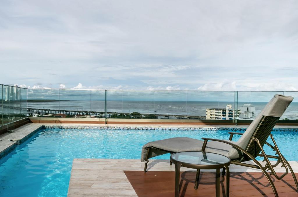 a swimming pool with a chair and a table at Boutique Apartments Panamá Coco del Mar in Panama City