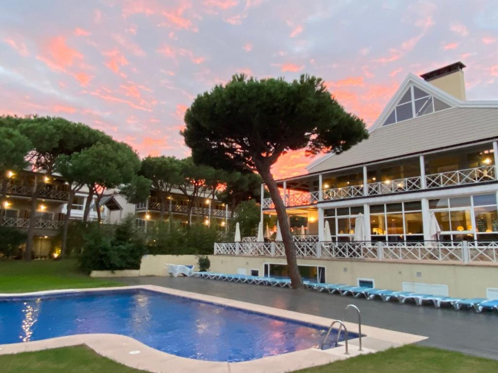 a resort with a swimming pool in front of a building at Hotel Nuevo Portil Golf in El Rompido