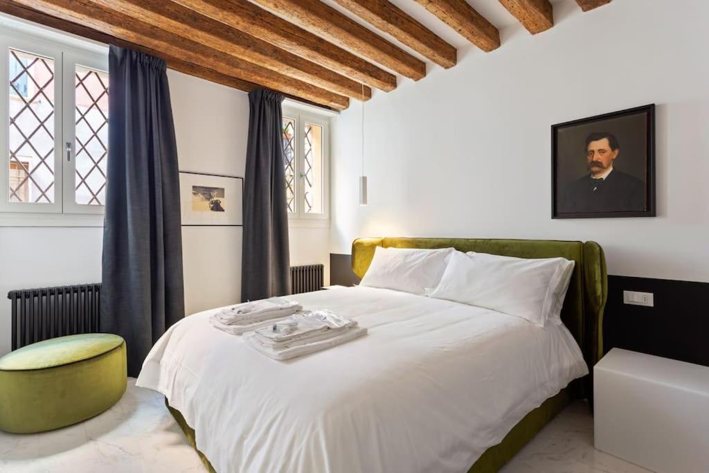 a bedroom with a white bed and a green chair at Dimora San Lorenzo Luxury Apartment in Venice