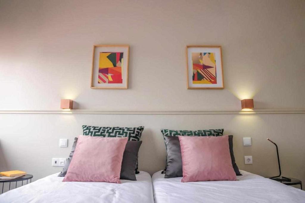 a bedroom with two beds and two pictures on the wall at Hotel Singular Porto Aeroporto in Maia
