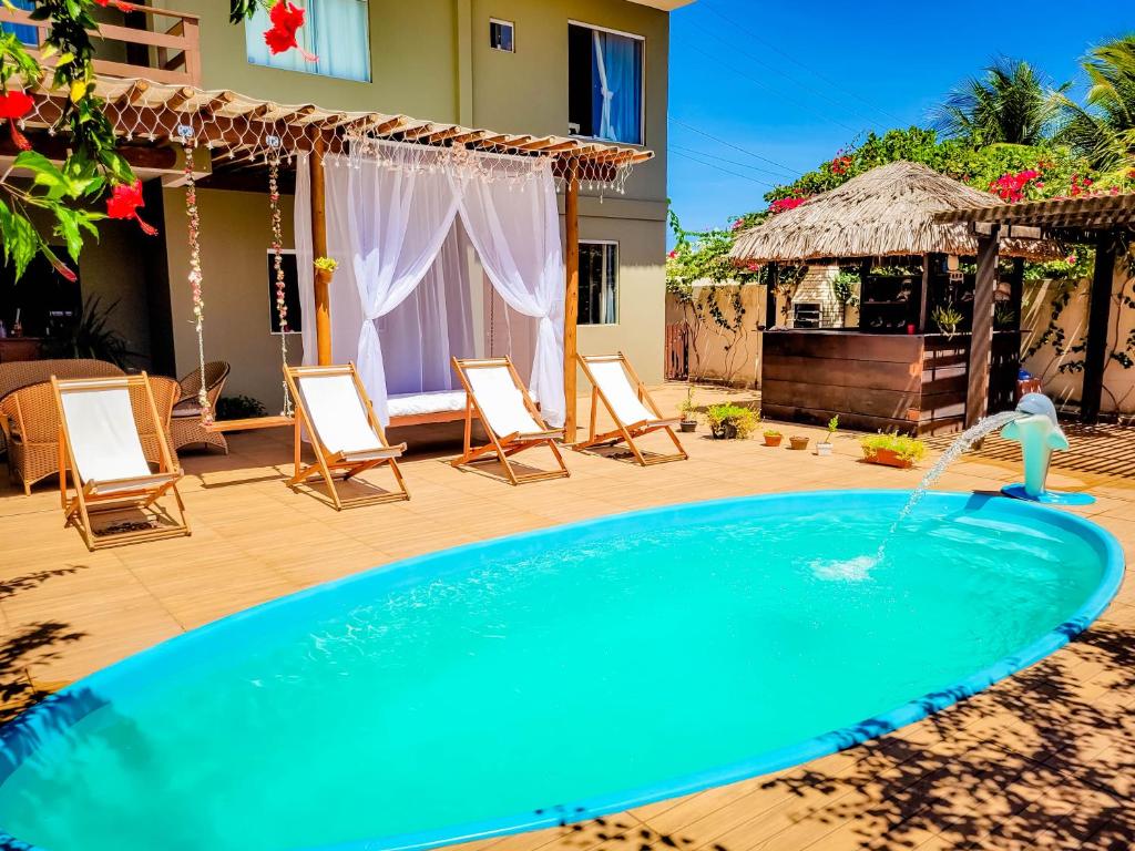 a swimming pool with chairs and a water fountain at Pousada Primavera in São Miguel do Gostoso