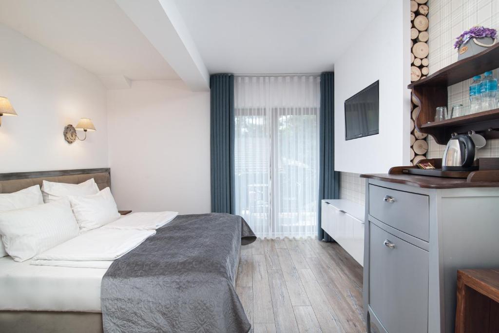 Cozy double bed room with gray bedding, wall-mounted TV, kitchenette cabinet, and balcony
