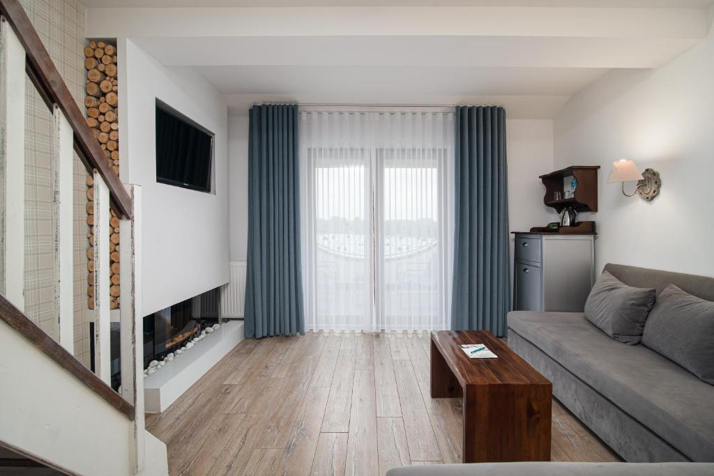 Modern living room with grey sofa, wooden coffee table, fireplace, and sheer-curtained balcony doors