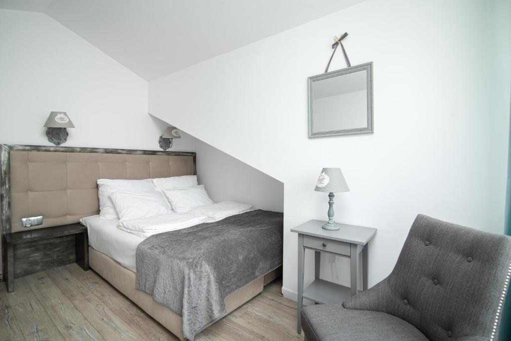 Cozy attic bedroom with double bed under sloped ceiling, grey armchair and bedside table.