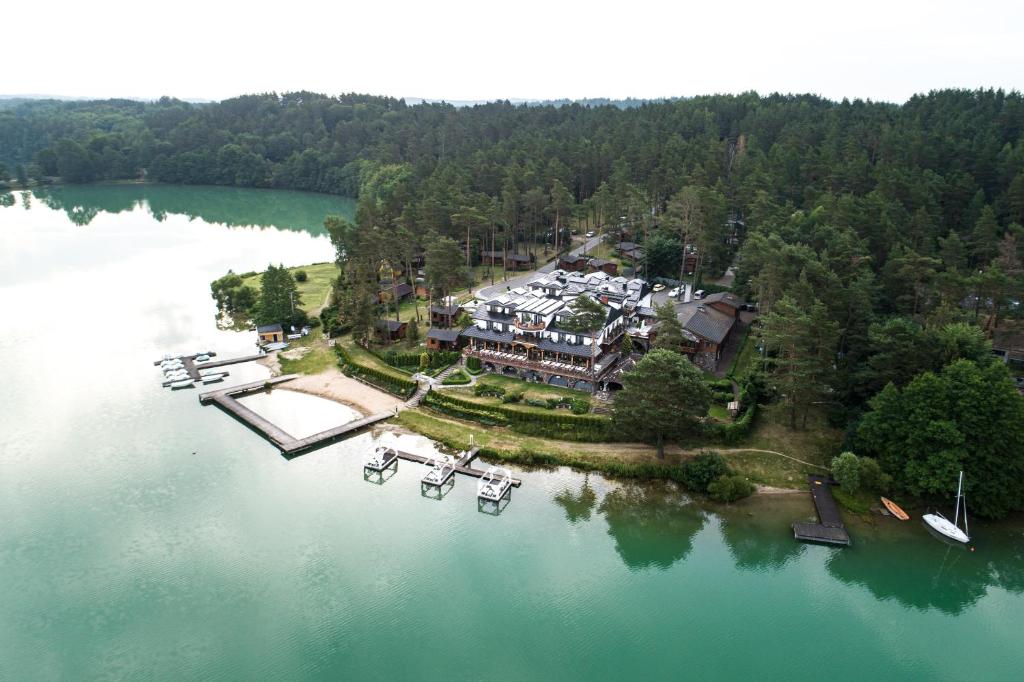 Aerial view of lakeside resort with docks, small boats and sandy bay surrounded by dense pine forest.