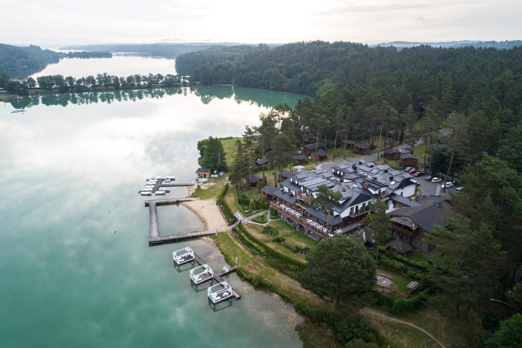 Panoramic aerial of resort peninsula, piers, emerald lake waters, and forested landscape.