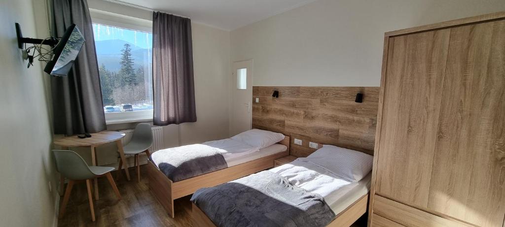 a room with two beds and a desk and a window at Apartament, Pokoje Koniczynka in Karpacz