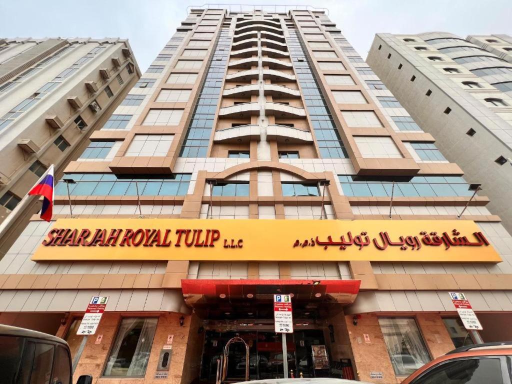 a tall building with a sign for a hotel at Royal Tulip Apartments in Sharjah