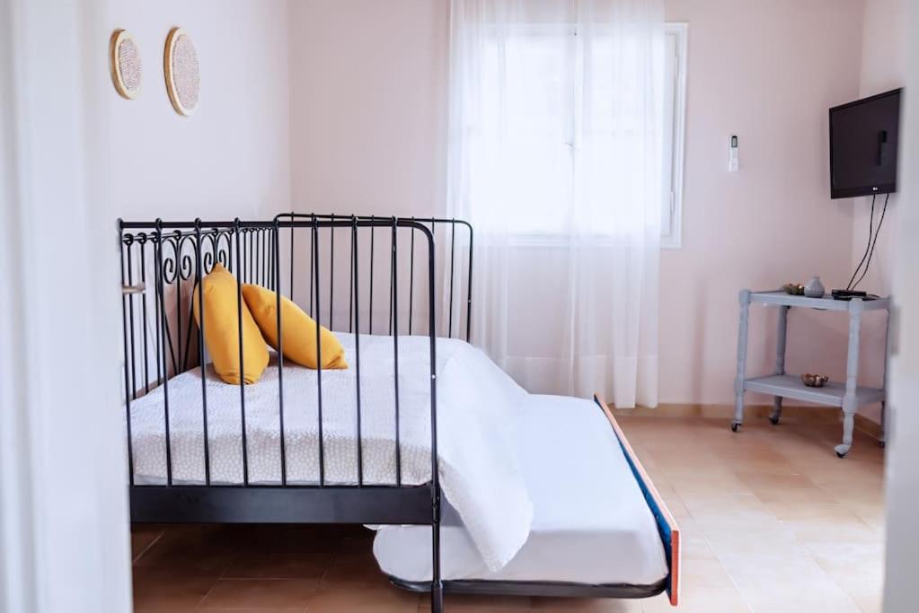 una culla nera con cuscini gialli in una camera da letto di The Homey a Sidari