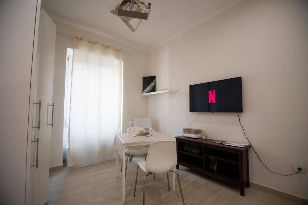 Dieses weiße Zimmer verfügt über einen Tisch und einen TV an der Wand. in der Unterkunft Wi-Fi & NETFLIX - Luxe Suite nel Cuore di Salerno in Salerno