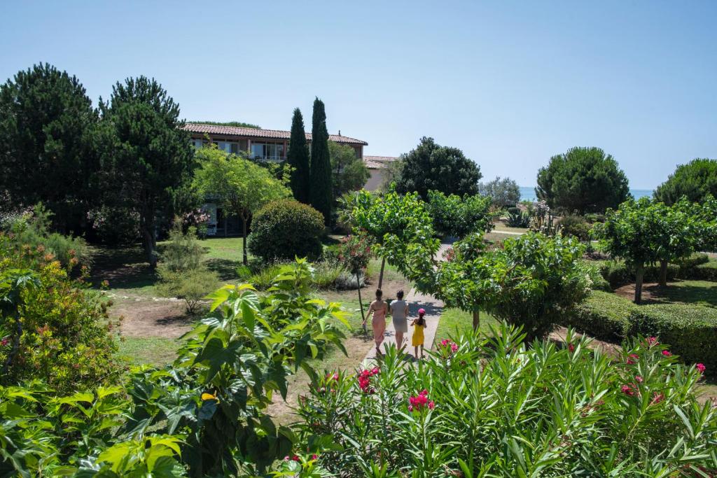 people walking through a garden with trees and flowers at SOWELL RESIDENCES Les Sablons in Le Grau-du-Roi