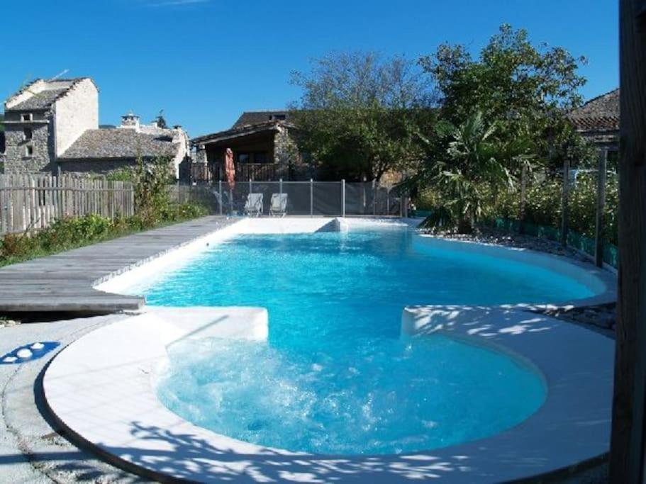 a large pool with blue water in a yard at Gîte de l'Ouradou in La Cresse