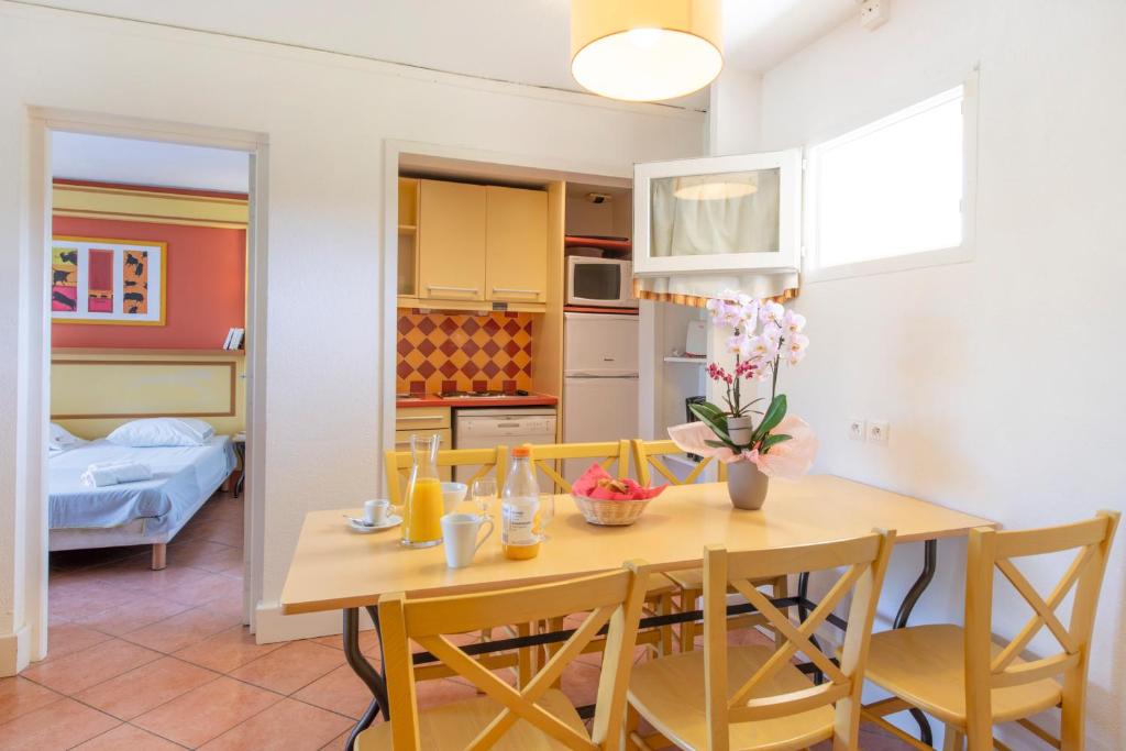 a kitchen and dining room with a table and chairs at SOWELL RESIDENCES Les Sablons in Le Grau-du-Roi