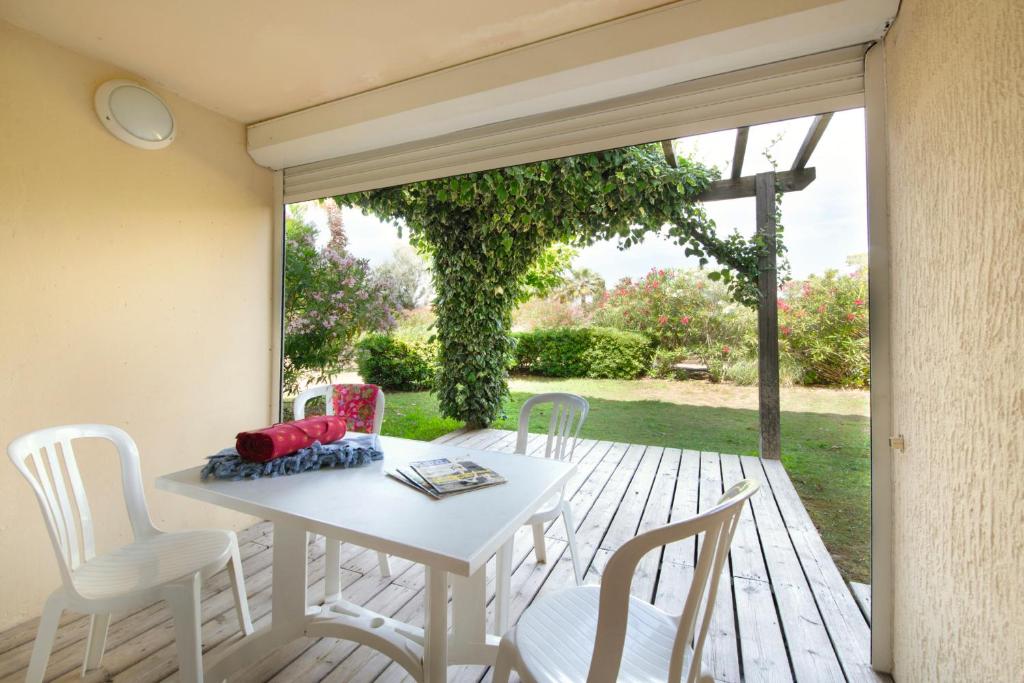 a white table and chairs on a wooden deck at SOWELL RESIDENCES Les Sablons in Le Grau-du-Roi