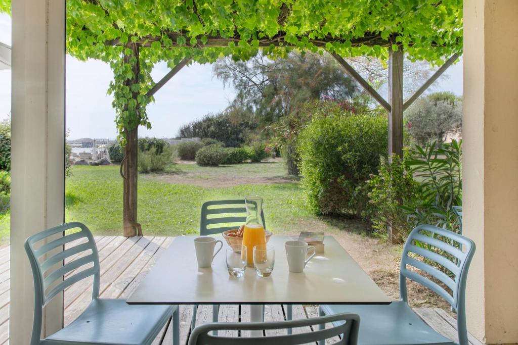 a table with two glasses of orange juice on a patio at SOWELL RESIDENCES Les Sablons in Le Grau-du-Roi