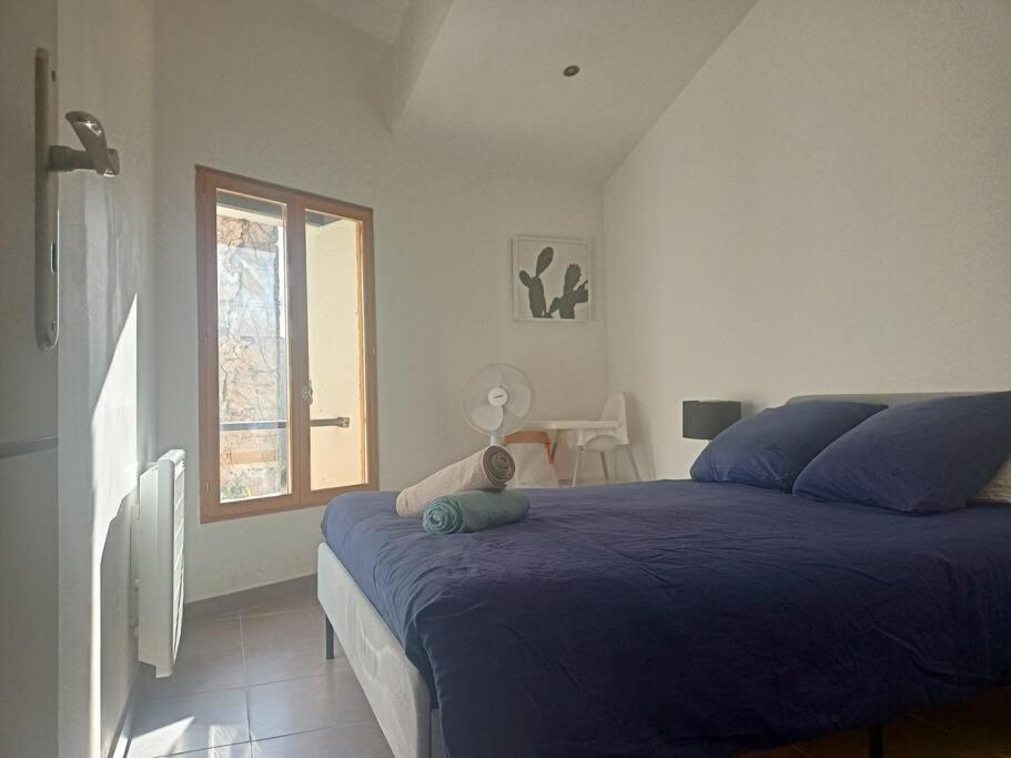 ein Schlafzimmer mit einem blauen Bett und einem Fenster in der Unterkunft Le clos du pin in Thèzan-lès-Béziers