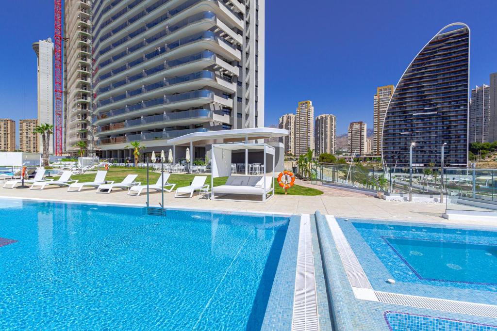 una piscina con sedie a sdraio e un edificio di SUNSET CLIFFS sea & sky apartments a Benidorm