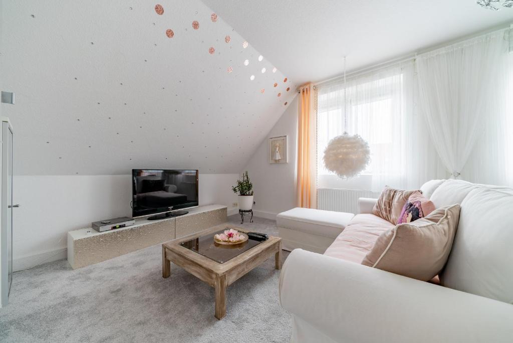 a white living room with a person sitting on a couch at Privatapartment in Laatzen