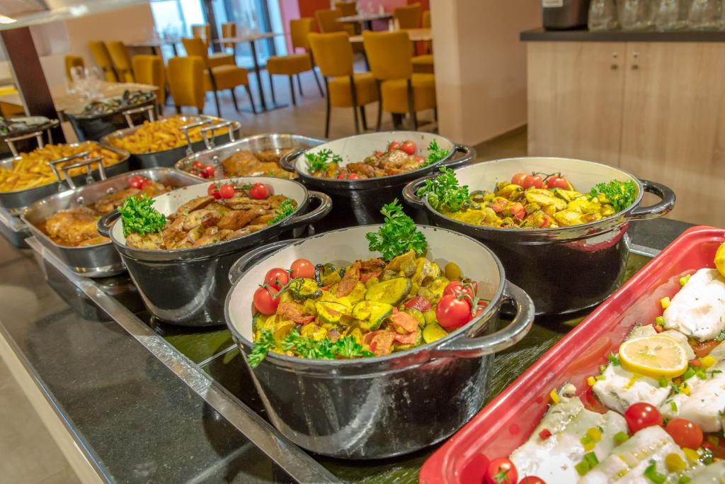 a buffet with many different types of food in metal containers at SOWELL RESIDENCES Les Sablons in Le Grau-du-Roi