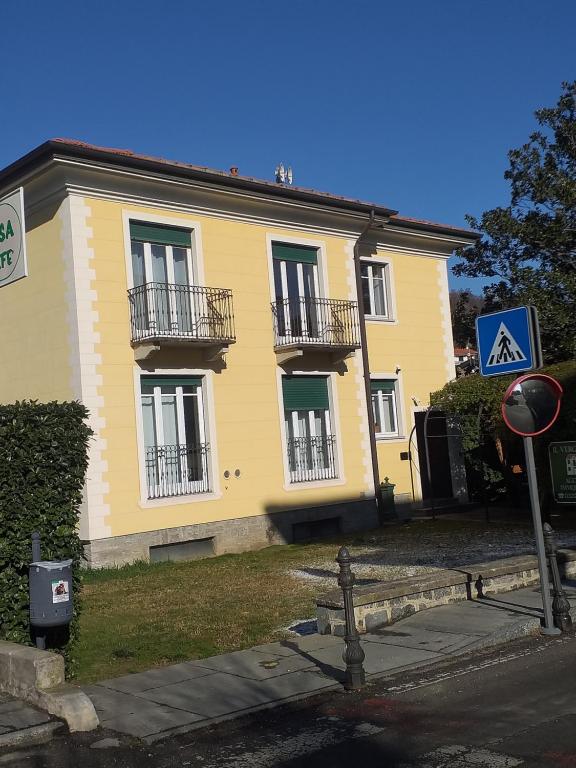 um edifício amarelo com duas varandas numa rua em Casa Patrone appartamento Luigi em Nebbiuno