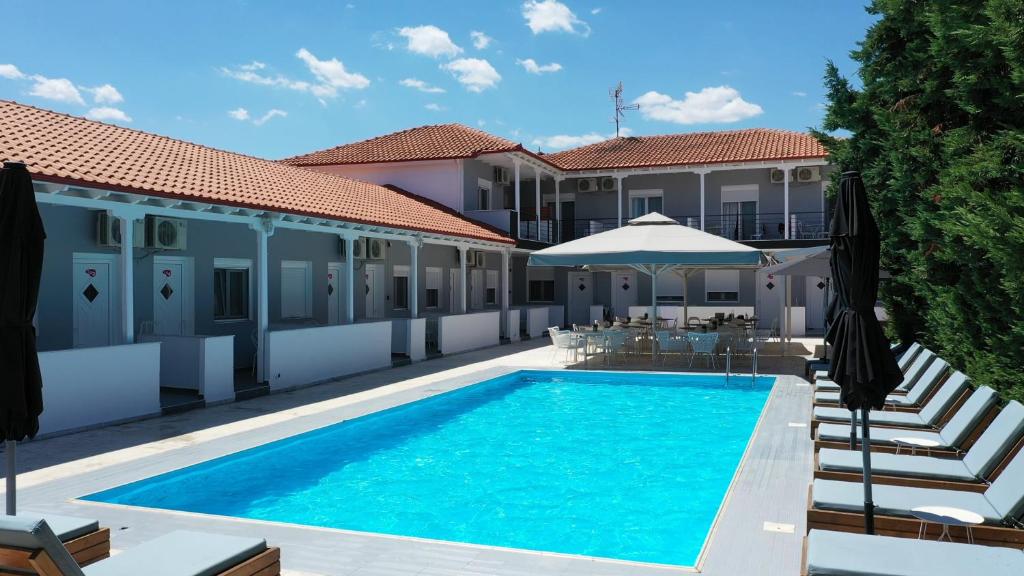 basen przed budynkiem z parasolem w obiekcie Philoxenia Suites w mieście Nea Vrasna