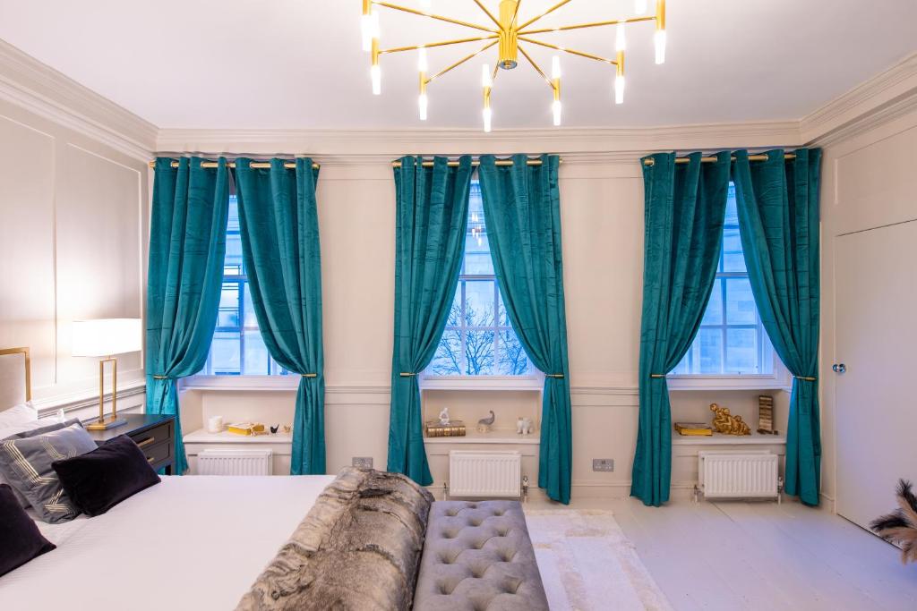 a bedroom with blue curtains and a large bed at Haus of Mason in London