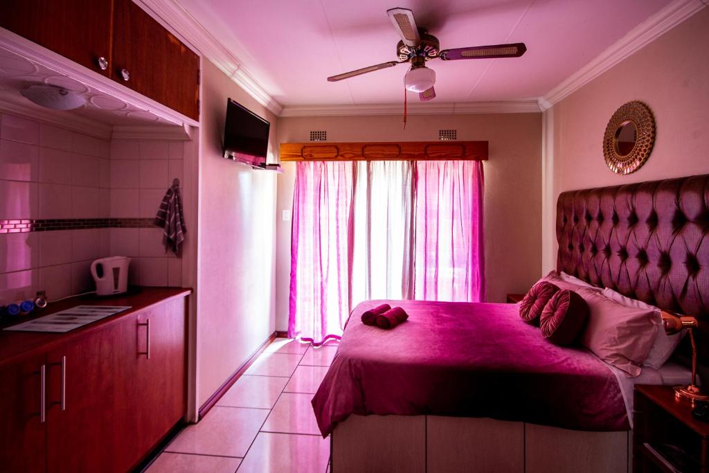 una camera con letto rosa e finestra di Invite Guest House Self Catering Accommodation a Vanderbijlpark